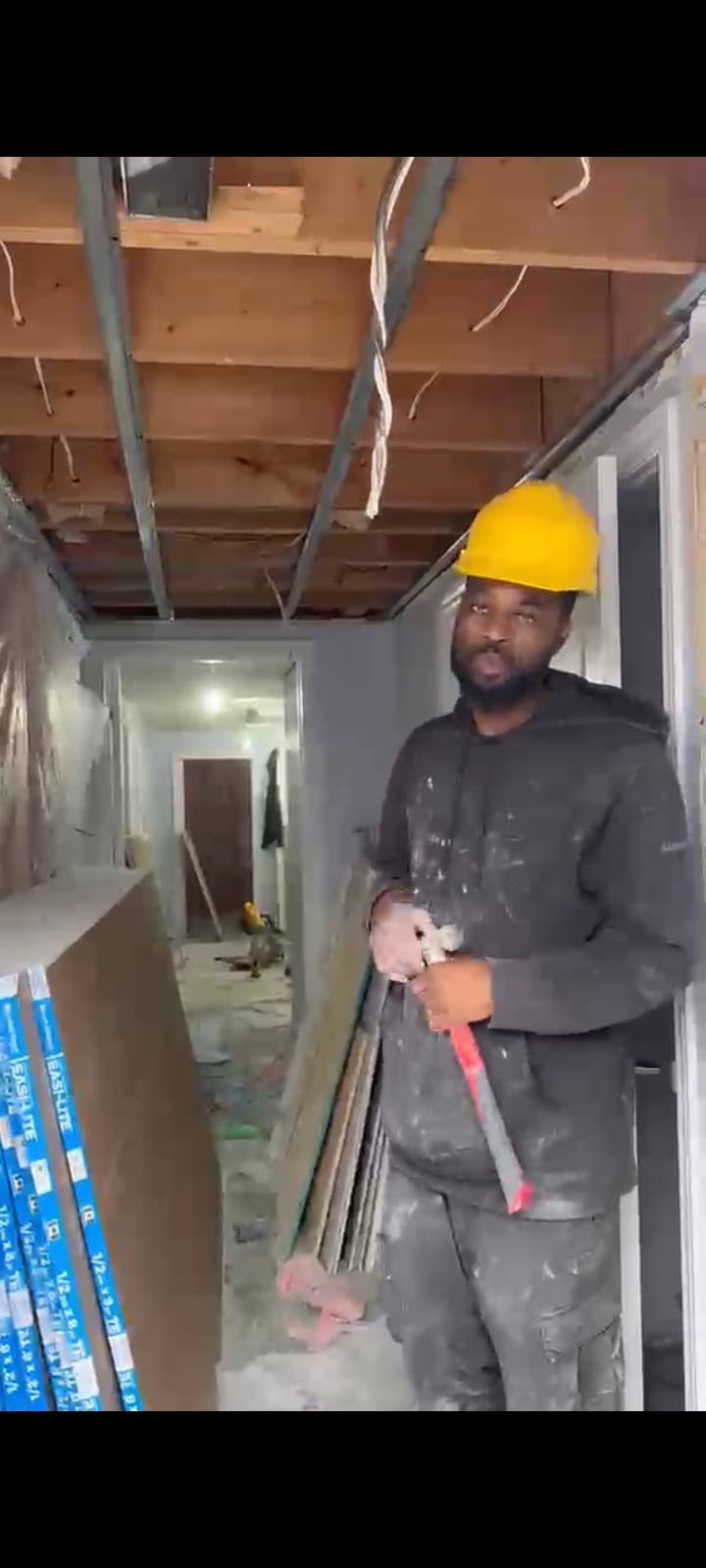 Mike wearing a yellow hard hat in the basement with the ceiling framing exposed